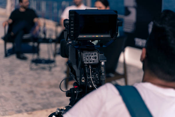 Behind the scene concept. Cameraman working on professional camera taking film interviewer interview celebrity people making news outdoors. USA, Industry, Movie, Television Industry, Film Director movie sound clips stock pictures, royalty-free photos & images