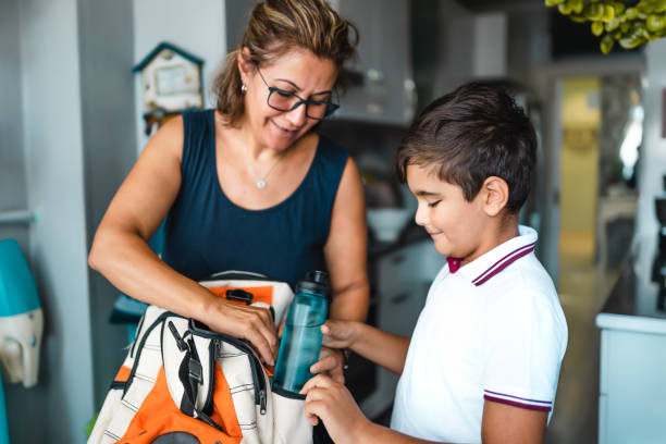 madre soltera ayudando a su hijo a prepararse para la escuela - lunch box child education school fotografías e imágenes de stock