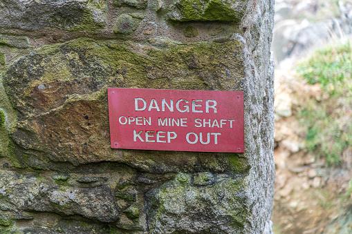 A warning sign on the wall of an old abandoned tin mine in Cornwall