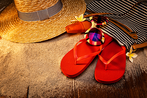 Multiple flip flops aligned in an orderly fashion on the wooden decking, colorful scene