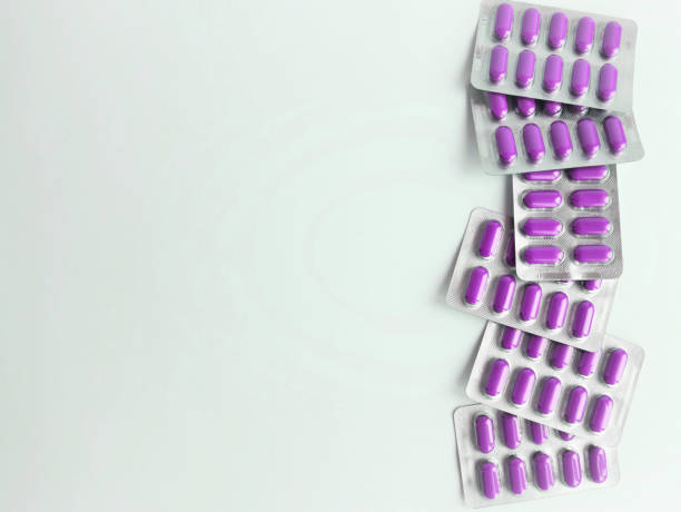 의료 테마에 대 한 배경, 아래 에 있는 물집에 흰색 흐리게 배경 보라색 캡슐에, 약물 치료 - pill purple capsule vitamin pill 뉴스 사진 이미지