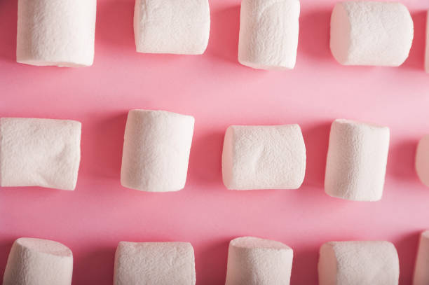 istock Marshmallows on a pink background close up and copy space. Marshmallow pattern top view on pink background. 1266327876