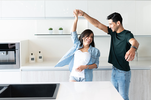 Cheerful young couple dancing by kitchen island at home