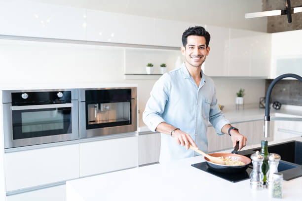 istock Hispanic Man Cooking Pasta At Kitchen Island 1266329997