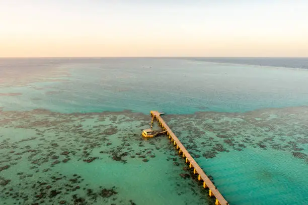 Photo of Sanganeb Reef National Park in Sudan, Red Sea, aerial view from Sanganeb Lighthouse with old wooden pier extending towards the sea