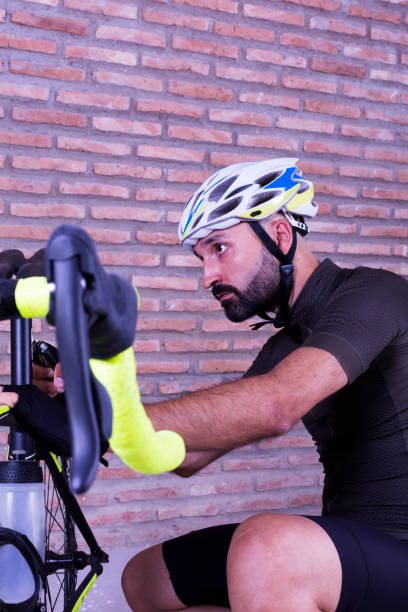istock Cyclist adjusting his bike next to a brick wall 1266338877