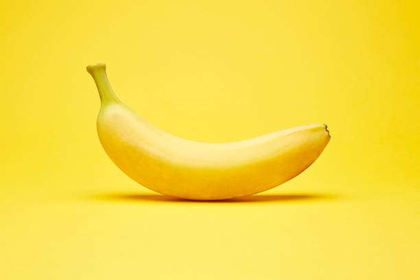 istock Single fresh raw clean isolated one alone horizontally oriented yellow banana on the bright solid yellow fond background 1266340637
