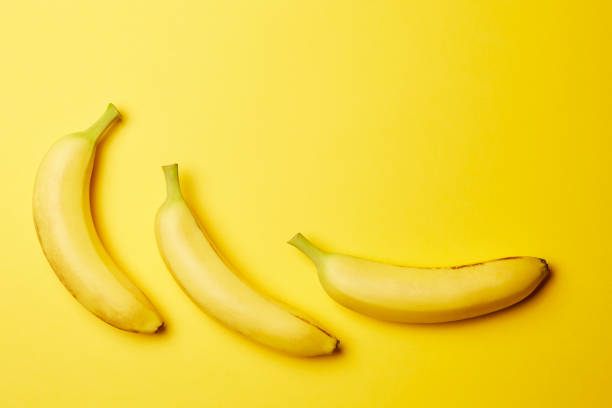 istock Three fresh raw clean isolated yellow bananas on the bright solid yellow fond background 1266340646