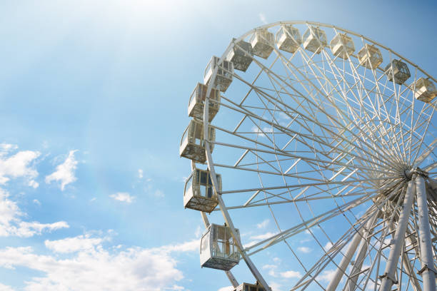 une roue d’examen est dans le parc des divertissements, sur un ciel bleu de fond - ferris wheel wheel blurred motion amusement park photos et images de collection