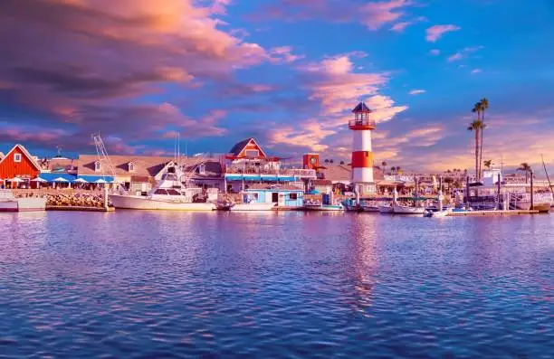 Colorful panorama at sunset with sky, waterfront and lighthouse reflected in the harbor.