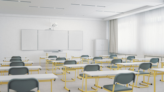 Interior of an empty modern classroom with interactive whiteboard and chairs organized for social distancing.