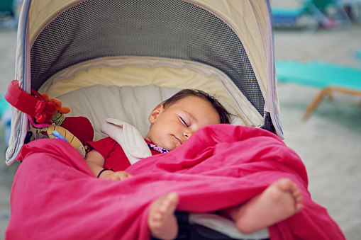Baby is sleeping in a baby stroller on the beach