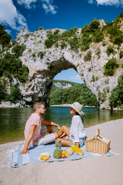 coppia sulla spiaggia sul fiume nell'ardeche france pont d arc, ardeche francia, vista dell'arco narurale a vallon pont d'arc nel canyon di ardeche in francia - canoeing people traveling camping couple foto e immagini stock