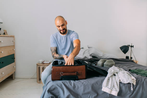 istock Time to Travel: Man Packing a Suitcase in the Bedroom 1266355041