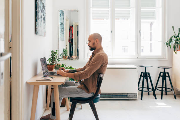 istock At the Home Office: a Young Man Working on his Laptop Computer at Home 1266355071