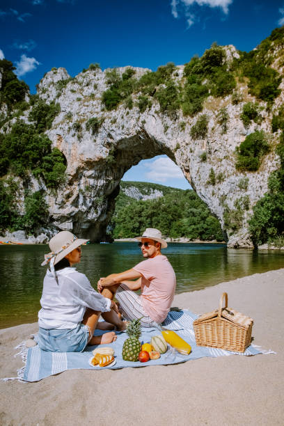 couple sur la plage au bord de la rivière dans l’ardèche france pont d arc, ardèche france, vue de l’arc narural à vallon pont d’arc dans le canyon de l’ardèche en france - canoeing people traveling camping couple photos et images de collection