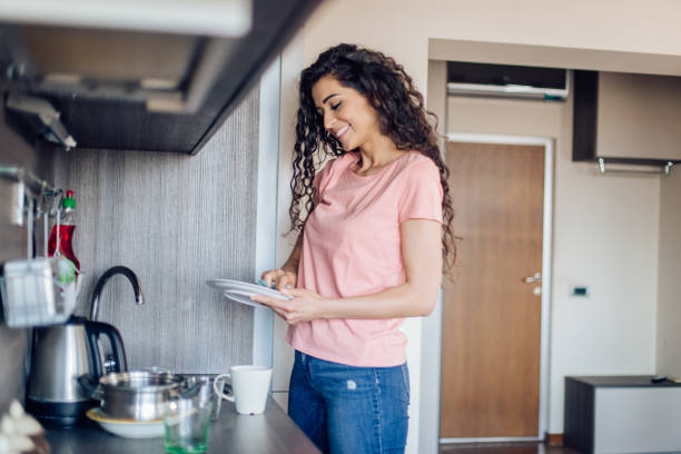istock Happy woman washing dishes at her kitchen 1266361502