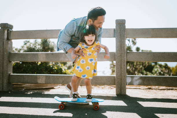 istock Father Helps Young Daughter Ride Skateboard 1266364168