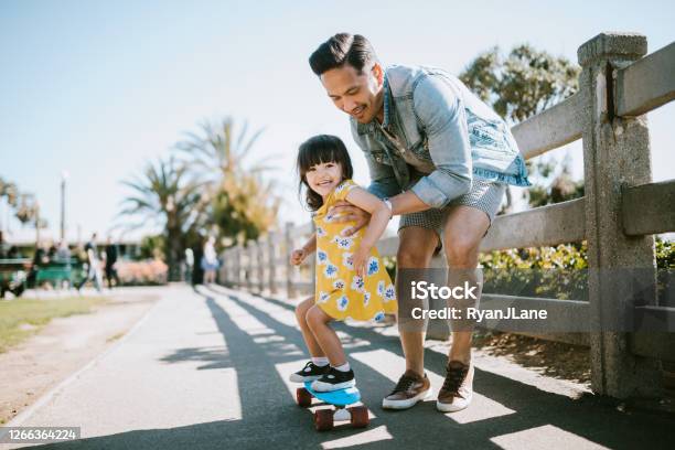 Father Helps Young Daughter Ride Skateboard Stock Photo - Download Image Now - Family, Child, Father