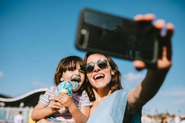 Family Eating Ice Cream at California Pier A mother takes a selfie of her and her daughter eating an ice cream cone at the Santa Monica Pier in Los Angeles, California. frozen sweet food photos stock pictures, royalty-free photos & images
