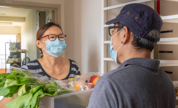 istock Courier wearing mask delivery groceries to customer 1266377534