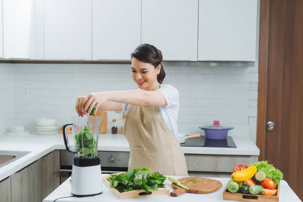 istock Vegetable smoothie woman blending green smoothies with blender home in kitchen 1266383828