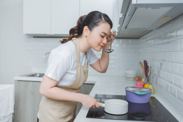 istock Young Woman Tasting Food With Spoon In Kitchen 1266383954