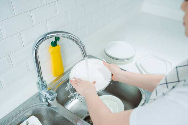 istock Young woman with apron washing dishes in modern kitchen 1266383968