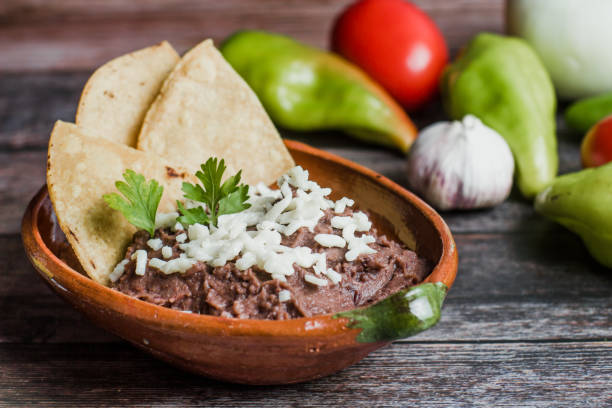 멕시코의 나무 테이블에 프리졸레 리프리토라고 불리는 멕시코 튀김 콩, 검은 콩 접시 - frijoles 뉴스 사진 이미지