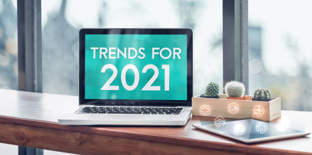 istock Trends for 2021 in laptop computer screen with icon floating on tablet on wood stood table in at window with blur background,Digital Business or marketing trending 1266385501