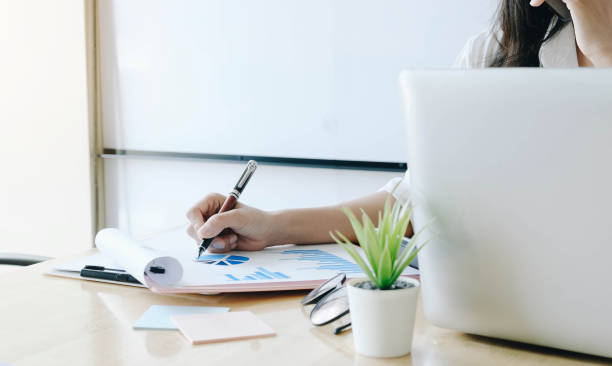 istock Consult financial concept. Business woman pointing at papwework and using laptop computer. 1266388183