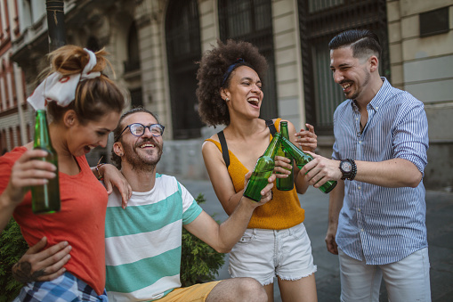 Group of mixed race people outdoors in the city, takes drinks and having a great time.