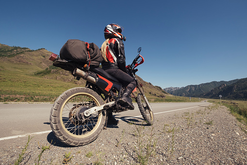 Woman traveling by enduro motorcycle in mountains road
