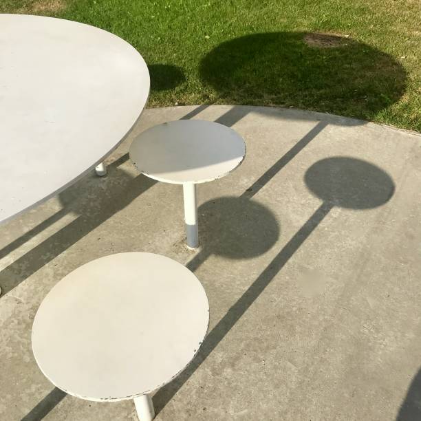 istock White steel outdoor table and stools making shadows on the concrete 1266397156