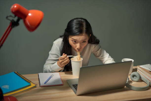 istock Woman studying online overtime at night has fast dinner 1266397425