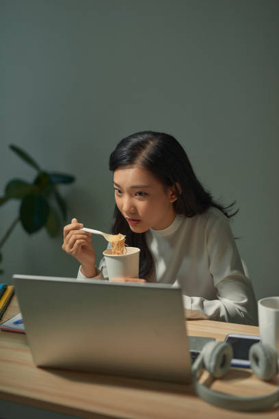 istock beautiful young lady with overtime doing deadline project and having late night meal 1266397443