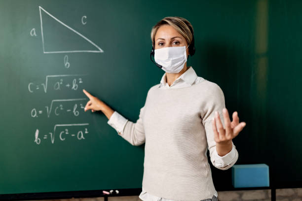 School teacher wearing face mask while teaching mathematic in the classroom.