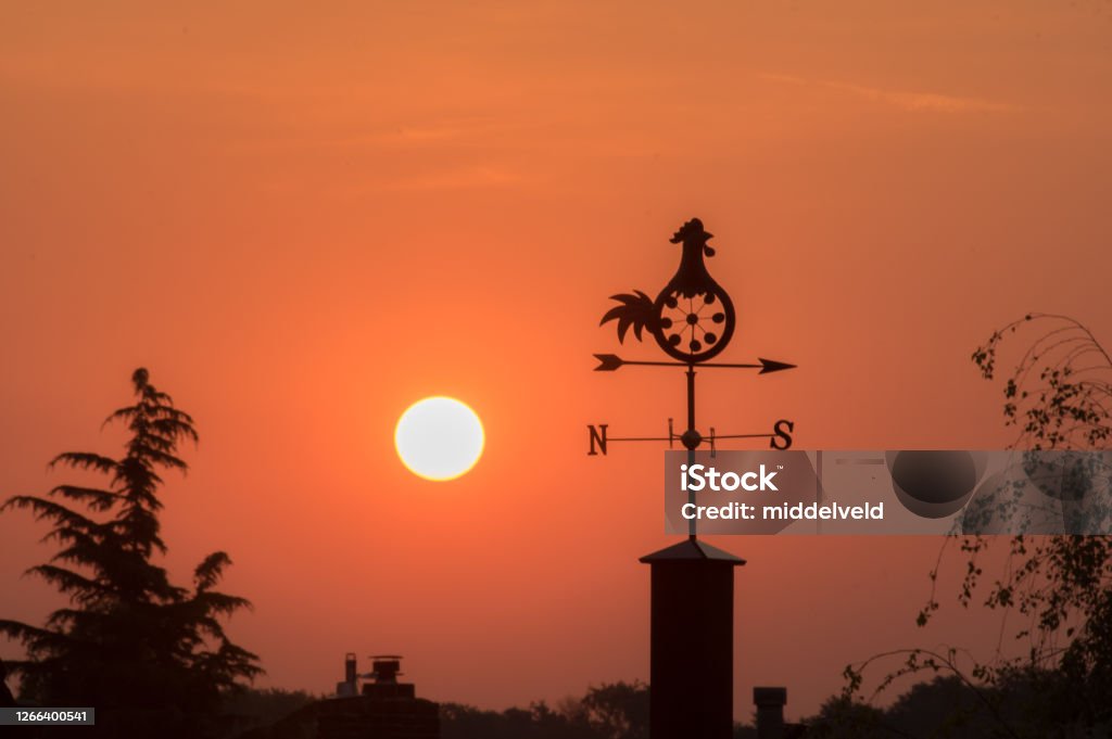 Direction vane at sunrise Weather van a sign of direction in the early morning Rooster Stock Photo