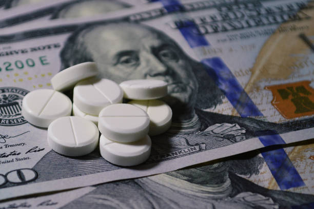 istock Tablets on 100 dollar banknotes. Pills on 100 dollar banknotes 1266404638
