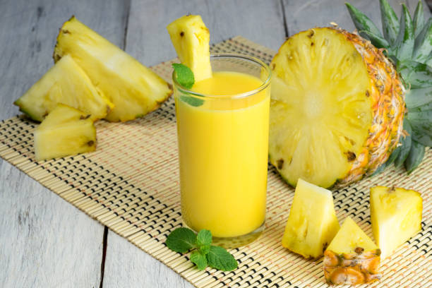 Fresh pineapple juice in the glass with fresh pineapple on wooden table. stock photo