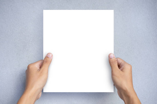 Hand holding a blank white paper sheet mock up on a gray background. Blank Brochure Template, Leaflet stock photo