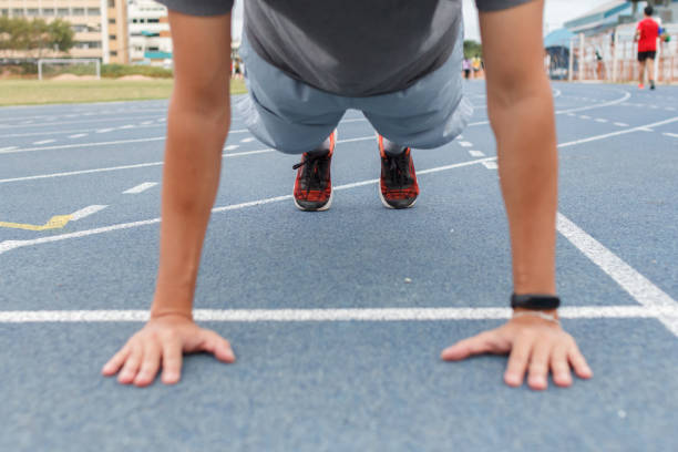 istock Sport man doing push ups exercise on the blue running track in stadium. 1266408666
