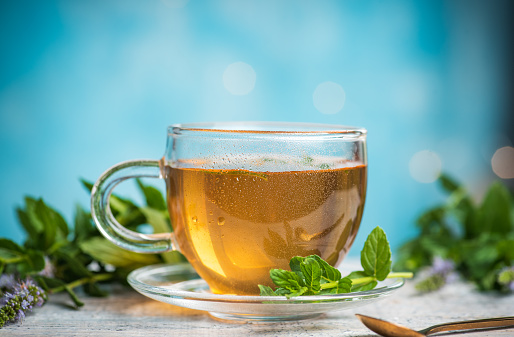 Hot natural antioxidant herbal tea aromatic beverage prepared by pouring hot or boiling water over cured or fresh leaves served in transparent glass cup isolated on white background