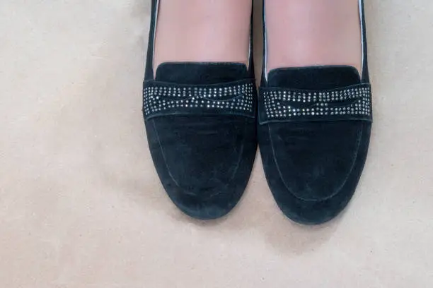 Woman's foot in suede black shoes with rhinestones. Copy space.