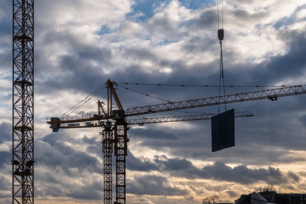 istock 3 cranes against cloudy sunset sky at construction site. 1266415199
