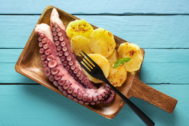 istock Cooked octopus with potatoes, on serving board, blue wooden background, top view 1266417980