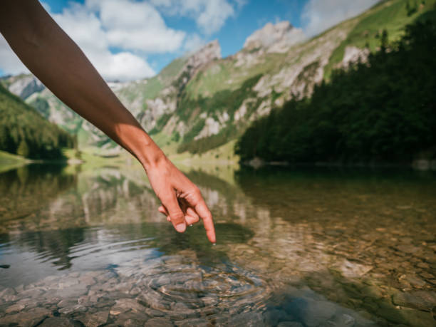 istock Female's finger touching water surface from alpine lake 1266418906