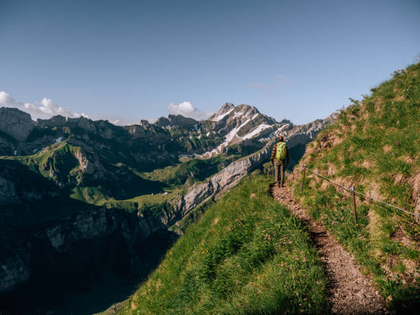 View of man hiking on mountain ridge looking at spectacular view in Appenzellerland Canton, Switzerland