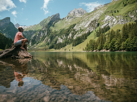 Rear view of woman hiking on by lakeshore looking at spectacular view in Appenzellerland Canton, Switzerland