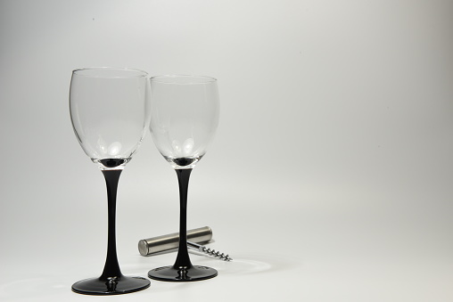 Two empty wine glasses placed side by side with a stainless steel wine bottle cork opener